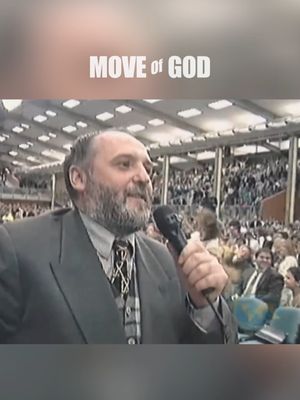The image features a middle-aged man with a beard speaking into a microphone. He is wearing a dark suit and a patterned tie. Above him is the text "MOVE of GOD" in a white, stylized font. The background shows a large crowd in what appears to be an auditorium or large event space.