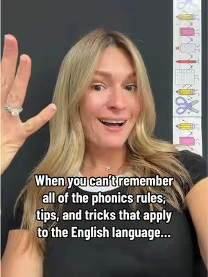 A woman with blonde hair smiles directly at the camera, gesturing with her right hand. Text overlays the image. Behind her is a portion of a classroom wall decorated with an illustrated chart.