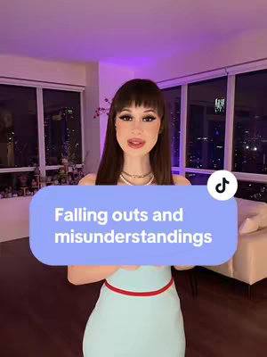 A woman with long dark hair and bangs stands in a well-lit room, possibly a high-rise apartment, in front of a large window with city lights visible. She is wearing a light blue dress with a red belt. A text overlay in a light blue rounded rectangle reads "Falling outs and misunderstandings". The backdrop suggests an elegant living space with a neutral color palette.