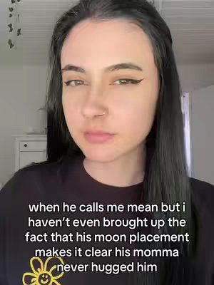 A selfie of a young woman with long, dark hair and dark eyeliner, looking directly at the camera with a slightly stern expression. The background is blurred, appearing to be a brightly lit room. Text is overlaid at the bottom of the image.