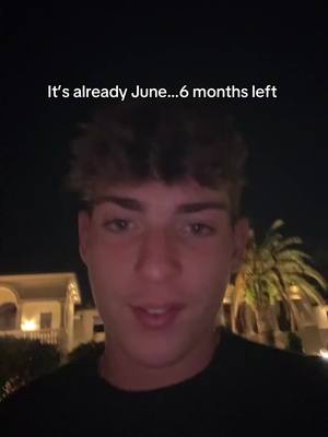 A young man is centered in a selfie-style shot, likely filmed at night. The background is dark, but hints of buildings and palm trees can be seen. The man has short, textured hair and is looking directly at the camera with a slight smile. Above him, a text overlay says 'It's already June...6 months left'.