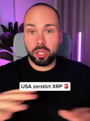 A close-up shot of a man talking to the camera, with overlaid text 'USA zerstört XRP' and a Swiss flag. The man has a bald head, a trimmed beard, and is wearing a black shirt. The background features a purple hue from the lighting setup.