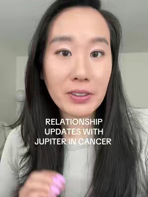 A woman with long dark hair is centered in the frame, looking at the camera and speaking. Overlayed text reads, 'RELATIONSHIP UPDATES WITH JUPITER IN CANCER.' The background appears to be an interior with a neutral color palette.