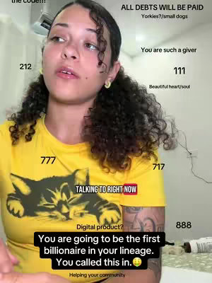 A woman with curly hair and a yellow t-shirt is looking up and to the left with various text elements and numerical annotations on the white background. The tee displays, "TALKING TO RIGHT NOW" in a red box on her chest, with a cat graphic below. Several numerical call-outs of the woman include 212, 111, 777, 717 and 888 The visual framing fills most of the frame, centering on the person. At the bottom, a black box highlights, “You are going to be the first billionaire in your lineage. You called this in. Helping your community.”