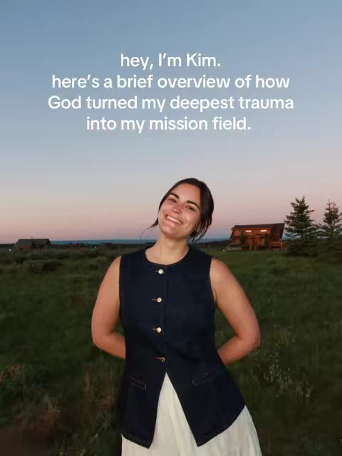 A woman with dark hair smiles at the camera outdoors, set against a scenic background with a field of greenery and a twilight sky. She wears a navy vest over a white dress. Text overlay displays an introduction and an overview of the topic.