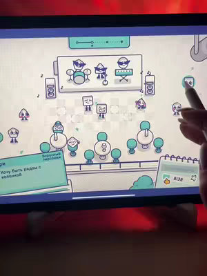An overhead shot of an iPad displaying a colorful, cartoonish game interface. The game appears to be a puzzle or simulation of a venue, with simplistic character designs and various interactive elements. A person's hand with a stylus hovers over the screen, suggesting gameplay interaction, while the background is a dark surface with surrounding lighting.
