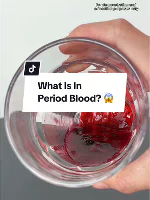 A hand holding a clear glass with a dark red liquid inside. In the liquid, there are chunks of dark red material, likely clots. The liquid takes up the lower half of the cup and is surrounded by clear liquid. Above the glass, the image shows a hand holding the glass. On top of the image is a white banner with black text that says, "What Is In Period Blood?" with a shocked face emoji.