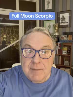 A medium shot of a man looking at the camera, with text overlaid at the top of the image. The man has short gray hair and is wearing glasses. He is wearing a blue shirt, and the background includes a door and framed pictures.