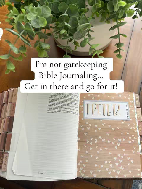 The image shows an open Bible on a wooden table with a plant in the background. The Bible is open to 1 Peter, with a decorative cover featuring hearts. Text overlay in a white box states, 'I'm not gatekeeping Bible Journaling... Get in there and go for it!'.