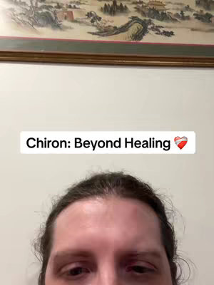 The cover image shows the top half of a person's face against a neutral background. Above the person is a framed picture with a landscape scene. A text overlay with the words "Chiron: Beyond Healing" and a heart symbol is positioned at the top, centrally.