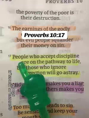 A close-up photograph of an open book, with highlighted text and a green decorative accent at the bottom. The text is in a paper with a bright yellow and fuchsia color scheme. The text are highlighted. The central text element is placed in a way that stands out. The overall composition is vertically oriented and focuses on textual content within a religious or spiritual context.