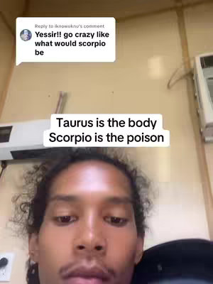 A selfie-style video shows a person looking into the camera from a close range, against a light yellow wall. A text overlay declares "Taurus is the body Scorpio is the poison" at the center of the frame above person's face. There's a comment section on the upper left corner that states "Yessir!! go crazy like what would scorpio be". The person has short curly hair.