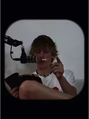 A young man is seen in a video frame, holding a microphone and a book. The scene is framed within a circular border, with the man making a pointing gesture and the word 'you' overlaid on the image.