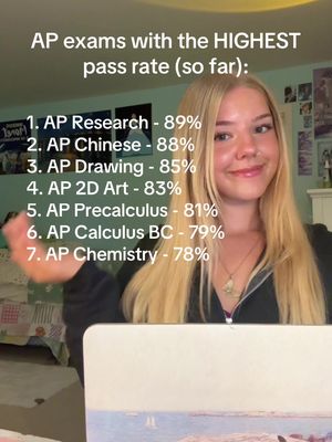 A young woman with blonde hair is smiling at the camera. Behind her, a list is displayed on a laptop screen showing AP exam scores with their pass rates. The background is a light green wall with some wall decoration on the right side.