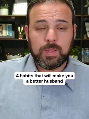 A man with a beard and wearing a light blue collared shirt is centered in the frame. The background includes shelves and some decorations. Text overlayed on the video reads, "4 habits that will make you a better husband".