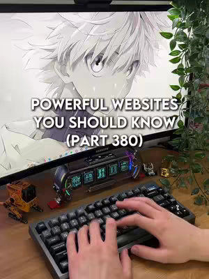 The cover image shows a workspace with a computer monitor displaying a black and white anime-style image. In front of the monitor is a mechanical keyboard with hands typing on it. Various decorative elements like small robots and a digital clock sit on the desk. The background includes a blurred green leaf vine.