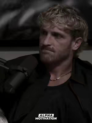 The cover image features a man with short, wavy blond hair and a trimmed beard. He wears a black shirt and jacket combo with a beaded necklace. The background is blurred, featuring what appears to be a piece of artwork or a dark, textured wall. The shot is framed from the chest up. A white text overlay, 'ALPHA MOTIVATION', is featured at the bottom of the image.
