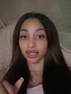 The cover image features a close-up of a woman's face. She has long, dark hair, and her lips are tinted with red lipstick. She is wearing a white tank top and a cross necklace. The background is blurred. The composition is focused on her face with her lips in motion.