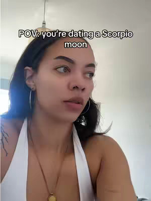 The cover photo features a woman looking to the side in a POV style while slightly smiling. The text overlay reads 'POV: you're dating a Scorpio moon'. The background is a room with natural lighting. She is wearing a white halter top and a gold necklace.