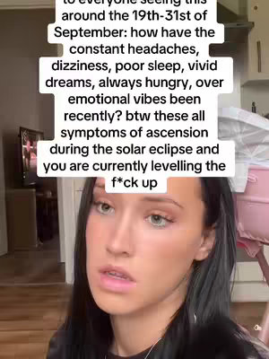 A young woman with dark hair and fair skin looks toward the camera with a neutral expression. The background is blurred, suggesting an indoor setting. Text overlays in a white box describes ascension symptoms during the solar eclipse.