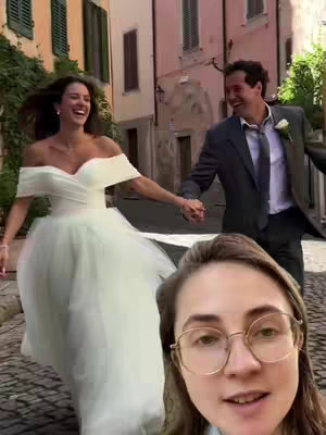The cover image shows a candid moment of a bride and groom joyfully running down a cobblestone street. The bride is in a flowing white wedding gown, and the groom is in a suit. The foreground features a woman in glasses, looking at the camera. The background is a European-style street with colorful buildings.