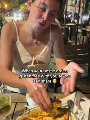 A woman is seated at an outdoor restaurant table, interacting with food on a plate. The background shows a blurred street scene, suggesting a casual dining environment. Text overlays on the image.