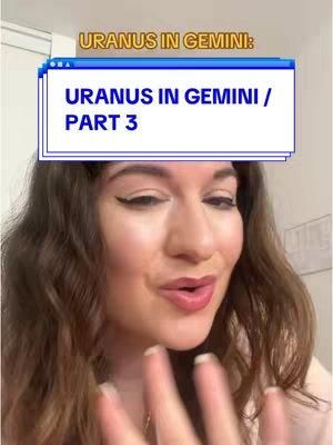 A woman with long brown wavy hair is in the center of the frame, looking towards the camera. She has fair skin, dark eyeliner, and pink lipstick. Above her head is a white and blue box with text that reads "URANUS IN GEMINI: URANUS IN GEMINI / PART 3" in white font. The background appears to be an off-white or cream-colored wall. The woman is wearing a light pink top.