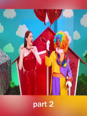 The cover image shows two people in a colorful, playful setting. On the left, a woman in a red dress is gesturing with excitement. On the right, a person in a clown costume with colorful hair. They are standing in front of a stylized red house against a backdrop of clouds and a blue sky.