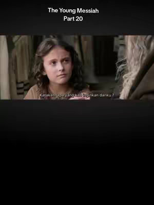 The cover image is a still from a film, featuring a young girl with brown curly hair, apparently portraying a young Jesus. She has a contemplative look, wearing a simple brown garment, and is positioned in front of others in a dim interior setting. Text on the image includes 'The Young Messiah Part 20' at the top and subtitles at the bottom.