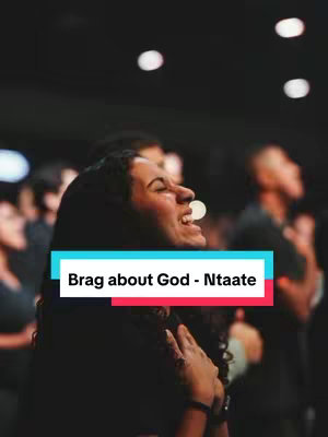 A woman with dark hair is shown in a medium shot, smiling with her head tilted back and her hands near her chest. She's in a crowd of people, and the background is blurred with lights. A banner with text is placed in front of the woman.
