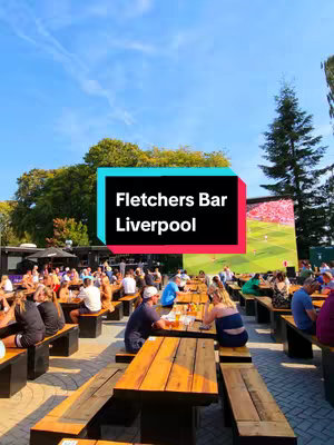 A vibrant outdoor scene at Fletchers Bar, with a large screen showing a football match. Tables and benches are filled with people enjoying drinks and the game under a blue sky. A text overlay identifies the bar.