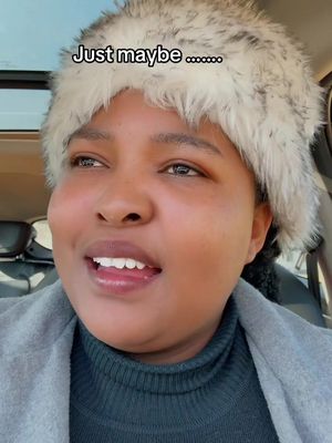 A woman is seated in a car, with a furry hat on her head, turned slightly toward the camera, with the caption "Just maybe..." overlayed towards the top.