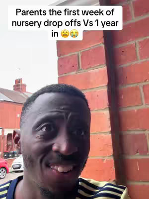 A selfie of a Black man with a slight smile, framed against a brick wall and a blurred street scene with a red car and a white car in the background. The man has short, dark hair, and is wearing a dark top. Text overlayed on the image reads 'Parents the first week of nursery drop offs Vs 1 year in' and shows a crying face emoji.