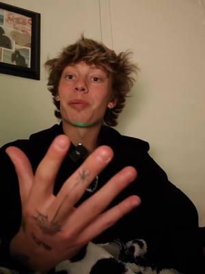 The cover image features a young man in a black hoodie. He is holding up his right hand, with several fingers extended. His hand has a tattoo. The background is plain. The color palette is muted, with the focus on the man and his gesture. The lighting is soft, suggesting an interior setting.