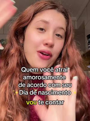 A selfie-style image featuring a young woman with long, reddish-brown hair and fair skin. She has a neutral expression, and the text overlay on the image asks: 'Quem você atrai amorosamente de acordo com seu Dia de nascimento? vou te contar' (Who attracts you amorously according to your date of birth? I'll tell you). The background is slightly out of focus, with partial view of a wall and kitchen