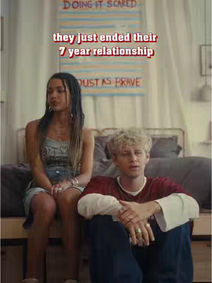 The image features a light-filled indoor scene. A woman with long, dark hair sits on a bed frame, wearing a casual outfit. Beside her is a man sits next to her. The background includes a headboard, and a banner reading 'DOING IT SCARED'. Text overlayed states, 'they just ended their 7 year relationship'. The composition is well-lit and includes neutral tones.