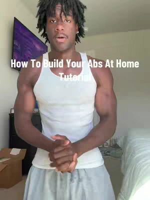 A man with dreadlocks and a white tank top stands in front of a camera, with a television visible in the background. Text across the image reads, "How To Build Your Abs At Home Tutorial."