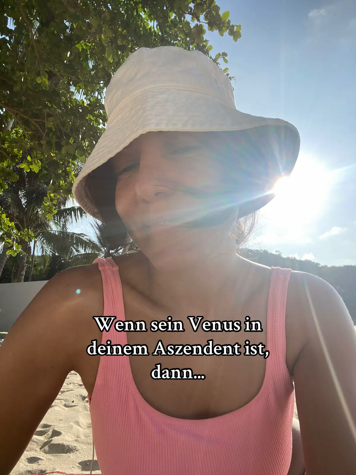 A selfie-style image with the creator in the foreground, wearing a white bucket hat and a pink top, partially obscured by sun glare from the sky that fills the upper portion of the frame.