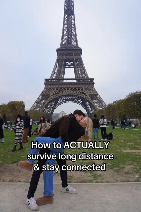 A couple embracing in front of the Eiffel Tower in Paris. A man is lifting the woman up; they appear to be kissing. The text overlay reads: 'How to ACTUALLY survive long distance & stay connected'.