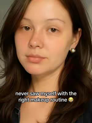 A selfie-style image showing a young woman from the chest up. She is pale-skinned with brown hair, pulled back from her forehead. She has dark eyes and a neutral expression. Her right ear has a gold earring. Below her, the text overlay reads 'never saw myself with the right makeup routine'.