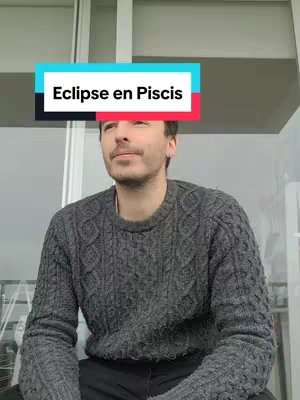 A man with a lightly trimmed beard and gray sweater is looking slightly upwards and to his right. The background is blurry but appears to be an outdoor setting. Overlay text in a box above his head reads "Eclipse en Piscis".