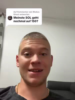 A young man with short, light brown hair is centered in a selfie video. He wears a black t-shirt and a gold chain. Behind him, a wall in light tones, and an unseen piece of furniture. A speech bubble from a comment appears on the top left, containing the hook text.