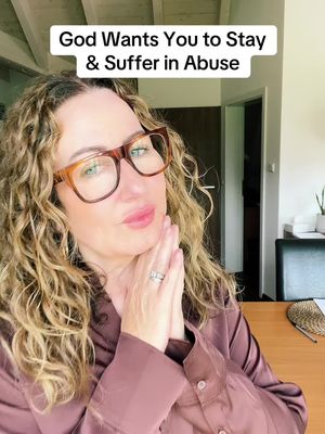 A woman with curly blonde hair wearing large, brown-framed glasses and a dark pink collared shirt. Her hands are clasped together in front of her face in a praying gesture. Above her are the words "God Wants You to Stay & Suffer in Abuse" in a white rectangular box.