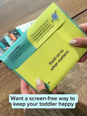 A person's hands hold a folded Chatbooks product, which is a set of photo books. The product is yellow and teal in color.