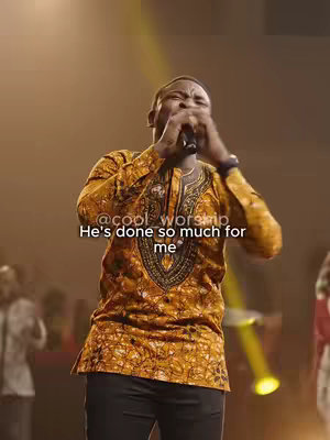 The image is of a man singing into a microphone on a stage. He's wearing a patterned, gold and brown shirt and black pants. The background is blurred, with a yellow spotlight shining from the side. Text overlays read '@cool_worship' and 'He's done so much for me'. The overall composition suggests a live performance.