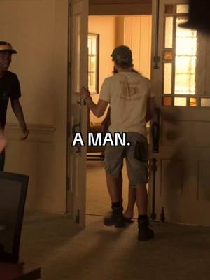 A man stands in a doorway, viewed from the back, seemingly about to leave. The doorway creates a bright opening with sunlight streaming through, contrasted by the darker interior. The text 'A MAN.' is overlaid on the image, positioned centrally.