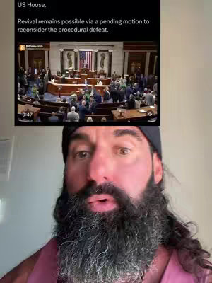The image features a man with a large beard and a black beanie, in front of a video showing the US House and news on the background. The man is looking directly to the camera.