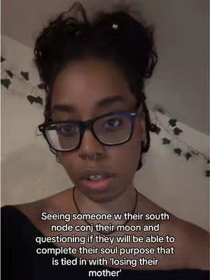 A selfie-style shot featuring a young woman with dark hair pulled back, wearing glasses and a nose ring. Text is overlaid at the bottom, posing a question about astrology. The background is simple and well-lit.