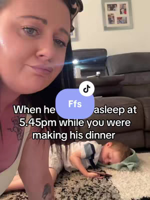 The cover image shows a woman in the foreground with dark hair smiling, and a young boy sleeping in the background, both on a carpet. In the bottom center is text overlaid on a purple circle with the letter "Ffs". Above the sleeping boy is text written.