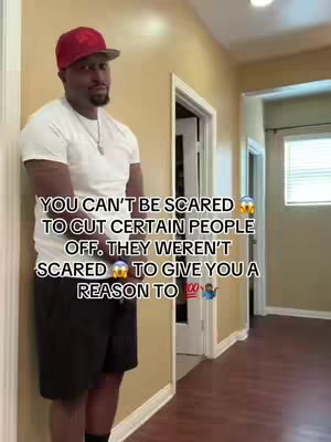A man wearing a red baseball cap, white t-shirt, and black shorts stands in a hallway. Text overlays read: 'YOU CAN'T BE SCARED TO CUT CERTAIN PEOPLE OFF. THEY WEREN'T SCARED TO GIVE YOU A REASON TO'. The background includes doorways and a neutral-colored wall.